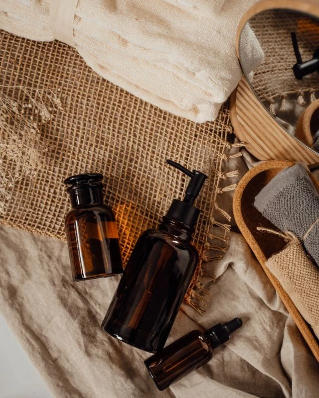 Flacons de soins cosmétiques en verre ambré posés sur un linge en lin, avec chaussons