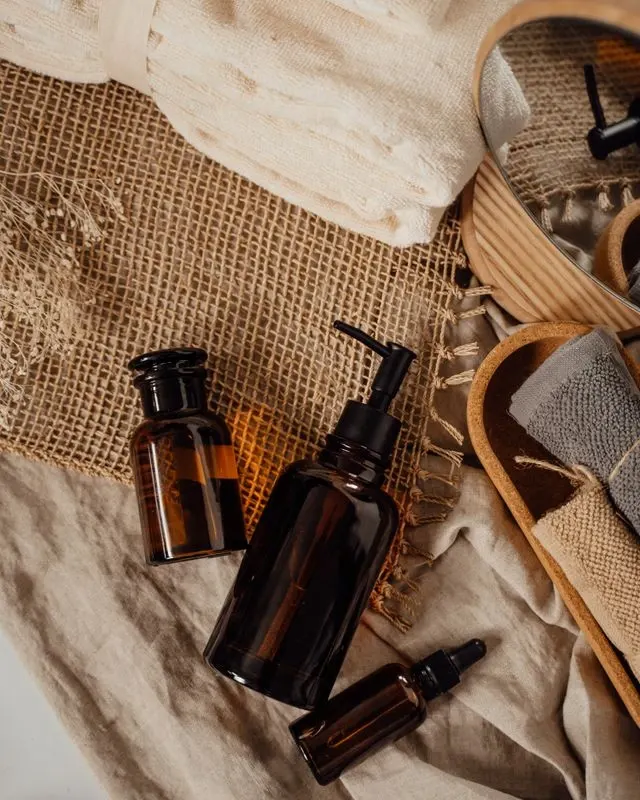Flacons de soins cosmétiques en verre ambré posés sur un linge en lin, avec chaussons