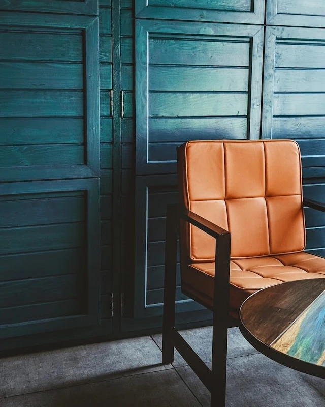 Fauteuil en cuir cognac devant un mur d’armoires en bois vert canard