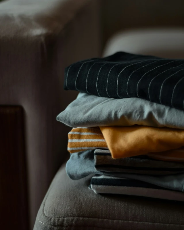 Pile de vêtements pliés aux couleurs automnales posée sur un fauteuil